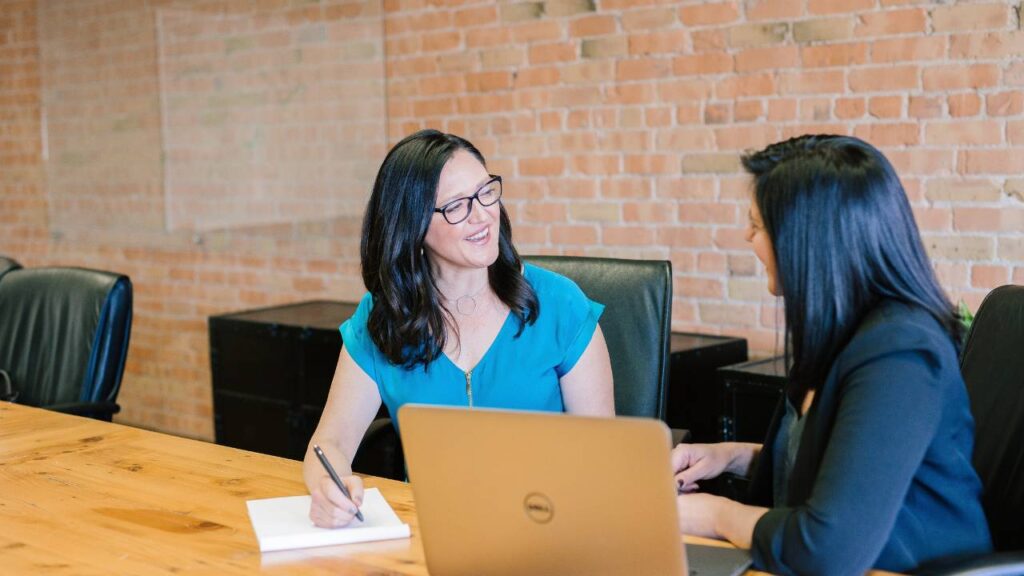 Two older female employees talking at work 