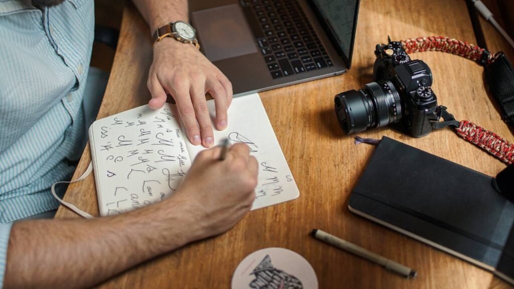A man using a notebook and a pen to create a logo