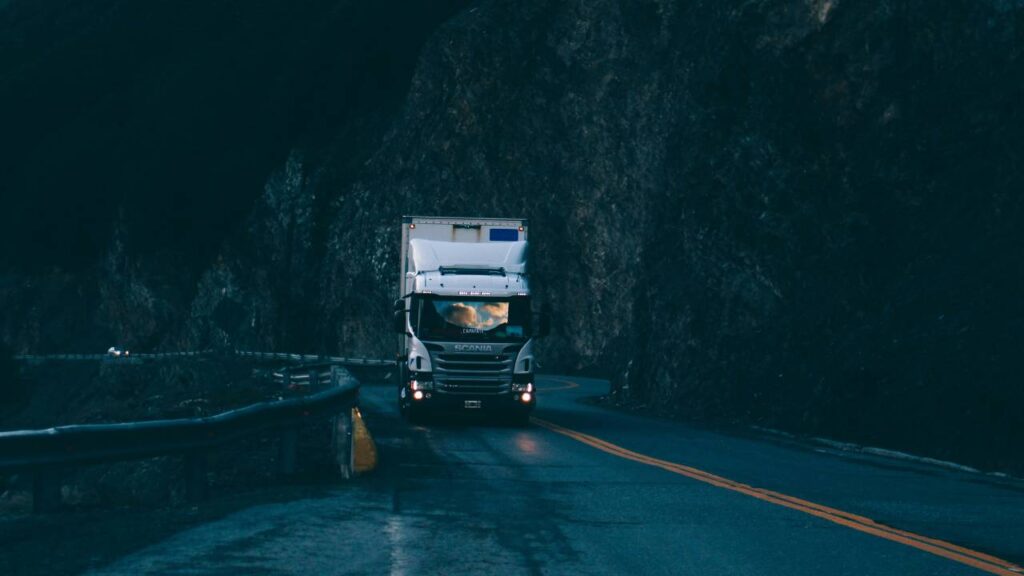 A large truck driving down a wet mountainside road