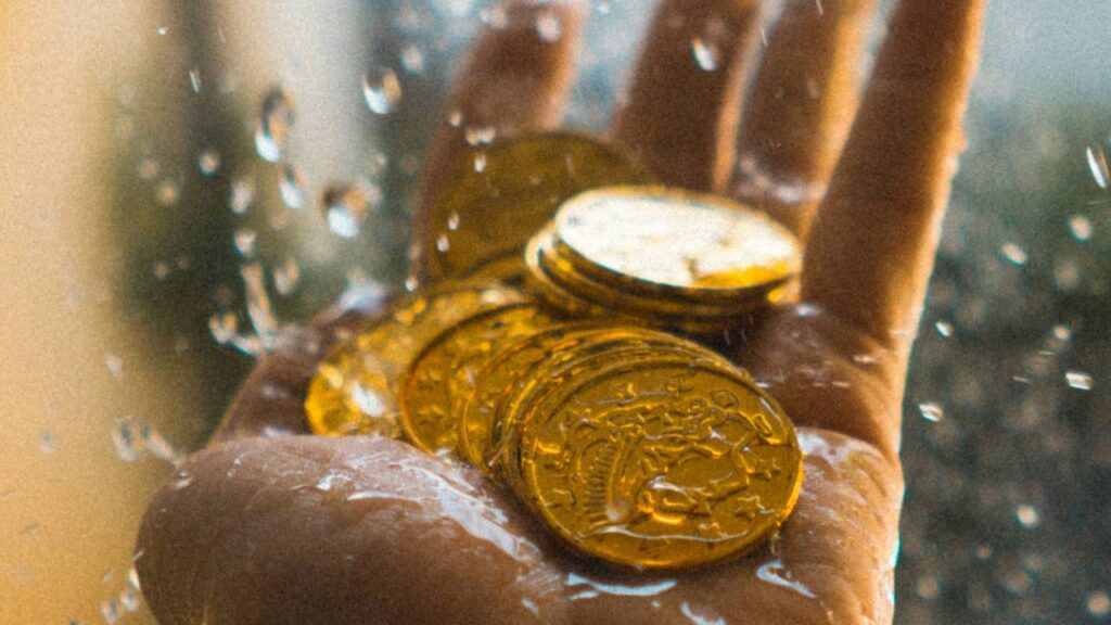 Water splashing golden coins in a man's hand