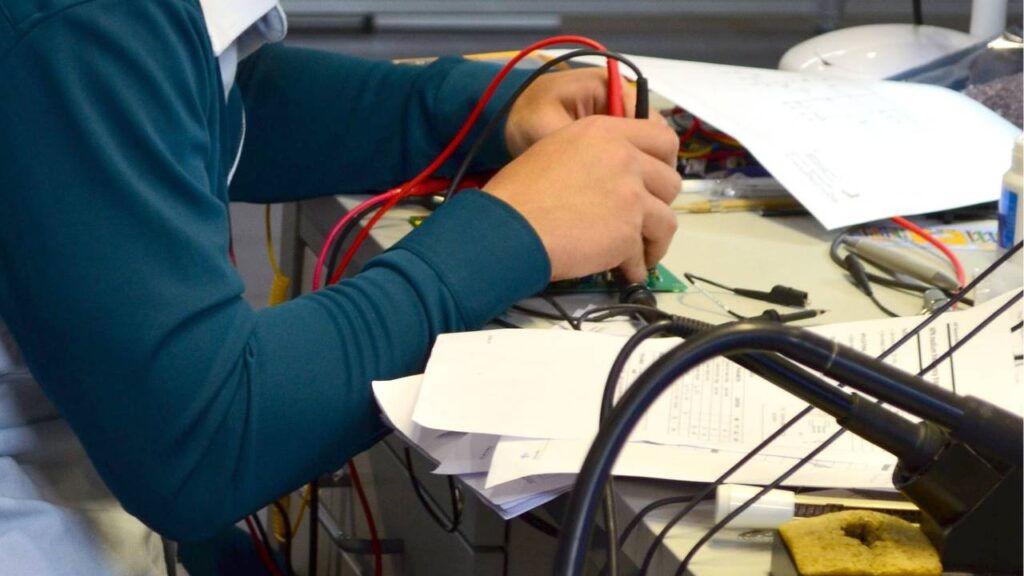 A photo of a man conducting a test with a multimeter